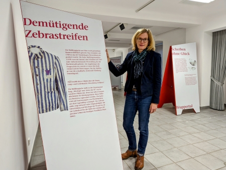 Kreismuseum Wewelsburg zeigt noch bis zum 29. Januar 2023 die Wanderausstellung „Mehr als man kennt – näher als man denkt. Objektgeschichten aus Gedenkstätten in NRW“.  Museumsleiterin Kirsten John-Stucke am Objekt „Häftlingsjacke von Max Schubert“ aus der Erinnerungs- und Gedenkstätte Wewelsburg 1933 – 1945. (Foto: ©Kreismuseum Wewelsburg)  Kreismuseum Wewelsburg zeigt noch bis zum 29. Januar 2023 die Wanderausstellung „Mehr als man kennt – näher als man denkt. Objektgeschichten aus Gedenkstätten in NRW“.  Museumsleiterin Kirsten John-Stucke am Objekt „Häftlingsjacke von Max Schubert“ aus der Erinnerungs- und Gedenkstätte Wewelsburg 1933 – 1945. (Foto: ©Kreismuseum Wewelsburg)